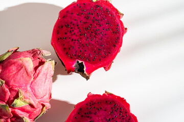 Juicy ripe pitahaya whole and scattered on a white background. View from above. Hard light, shadow...
