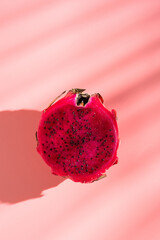 Juicy ripe pitahaya whole and scattered on a pink background. View from above. Hard light, shadow...