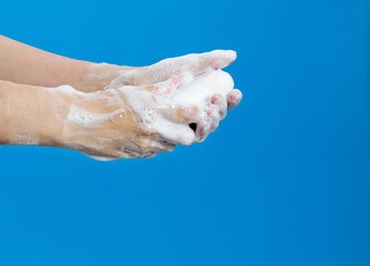 Fototapeta na wymiar Woman washing hands with soap on blue background