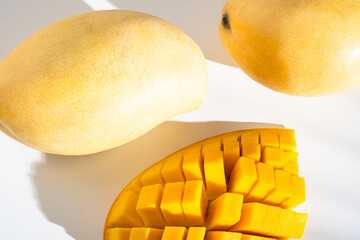 Juicy ripe yellow Thai mango on a white background. Hard light and shadow from a palm tree.