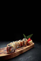 Sushi roll Golden dragon with eel, salmon, tobiko and cream cheese, on a wooden board