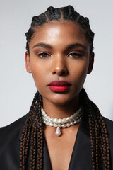 Portrait of African American woman with long braids wears pearls necklace.