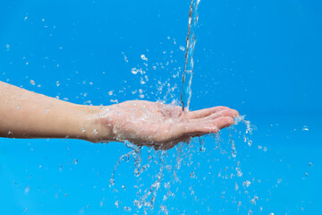 Fototapeta na wymiar Woman hand catching water on blue background
