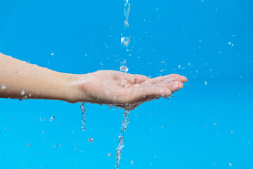 Woman hand catching water on blue background