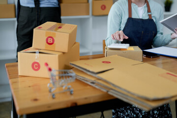 Close up startup small business owner working with tablet at workplace. freelance seller check product order, packing goods for delivery to customer. Online selling, e-commerce, shipping concept