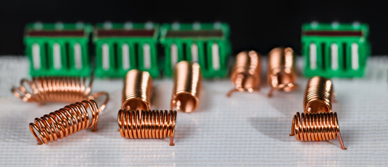 Orange radio-frequency inductors and green connectors in white PCB on black background. Copper wire...