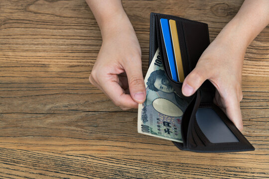 Woman hand holding a leather wallet with Japanese Yen