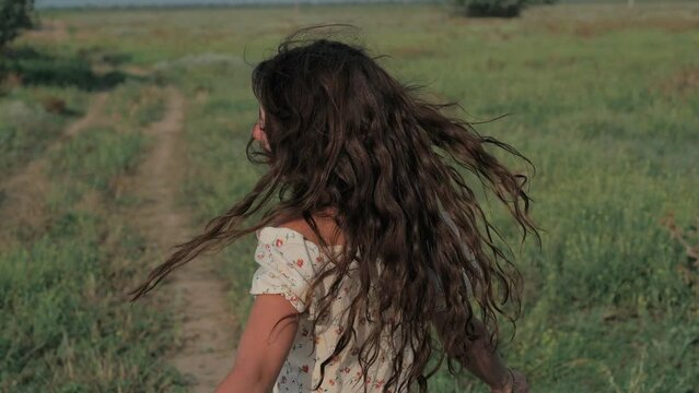 A beautiful girl in the steppe. Slow-motion authentic video. A beautiful young girl is circling and sincerely smiling at the camera.
