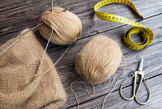 Knitting from wool yarn, scissors and centimeter on wood background