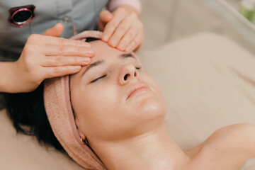 Fototapeta na wymiar Girl enjoying a relaxing facial massage at a cosmetology spa.