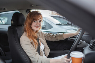 Beautiful young woman driving her new car at sunset. Woman in car. Close up portrait of pleasant looking female with glad positive expression, woman in casual wear driving a car