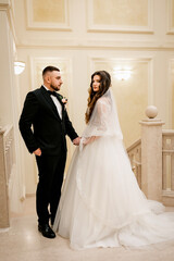 Beautiful wedding couple. Happy bride and luxurious husband. Marble staircase