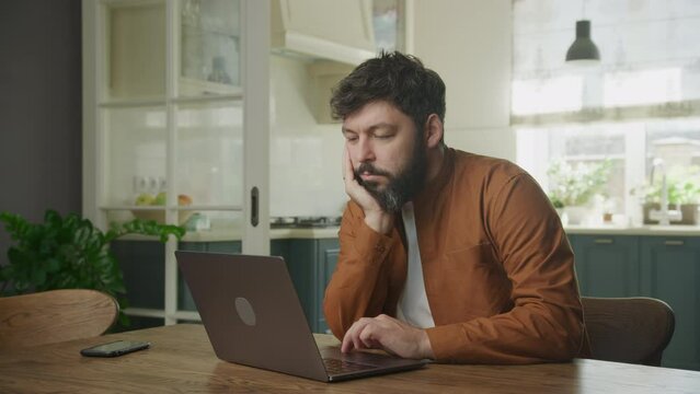 Young adult enterpreneur is bored working on a laptop indoors
