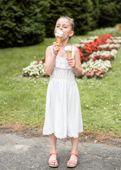 Little girl eats ice cream in the park. The child enjoys ice cream in the summer. The girl is holding an ice cream cone in her hands.