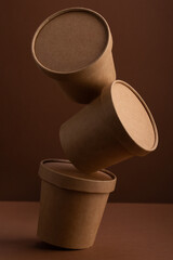 Balanced brown crafted paper cup for soup on dark brown background. Eco package. Zero Waste. Mock up for branding.
