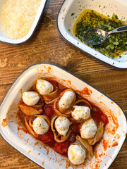 Baking tray with pasta lumaconi stuffed with mozzarella cheese and tomato sauce