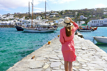 Fashion woman walking on pier of Mykonos old port, Greece - obrazy, fototapety, plakaty