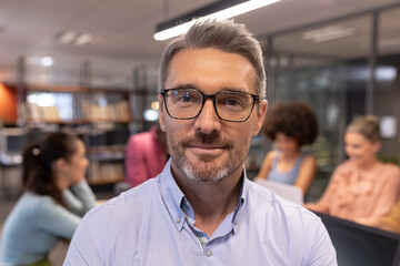 Portrait of smiling mature caucasian businessman wearing eyeglasses at workplace