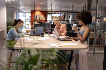 Biracial female advisors working at table in modern workplace