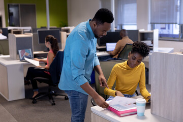 Obraz premium African american businessman and businesswoman discussing over document at modern workplace