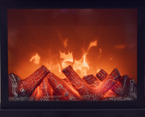 Fireplace with bright flames. Artificial decorative fireplace with imitation of fire. Modern home comfort technology. Full screen photo. Front view.