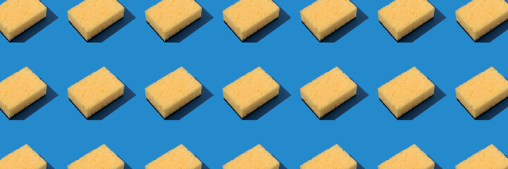Banner background, pattern with yellow dishcloth on blue background. Household products and cleaning concept, selective focus