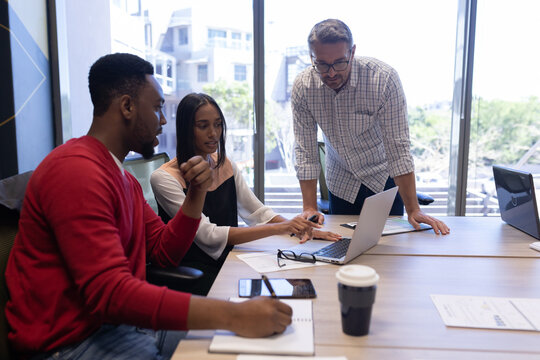 Young african american businesswoman discussing over laptop amidst biracial businessmen at office