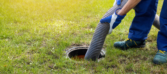 man pumping out house septic tank. drain and sewage cleaning service. copy space - obrazy, fototapety, plakaty