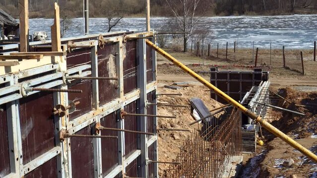 concrete the retaining wall and foundation for the terrace using formwork and scaffolding. Construction site of a house in spring season. High quality 4k footage