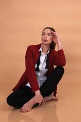 Portrait of a fashionista in the studio dressed in an elegant jacket and trousers, barefoot