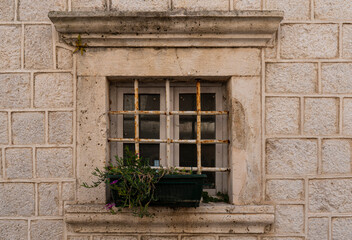 Fototapeta na wymiar Building's facade. Window with metal bars and flower pot. Architectural detail. Close-up