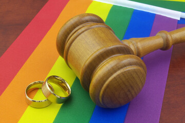 LGBT marriage equality and laws concept. Wedding rings, judge gavel and LGBT pride flags.	
