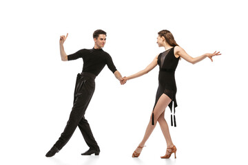 Dynamic portrait of young emotive dancers in black outfits dancing ballroom dance isolated on white background. Concept of art, beauty, music, style. - obrazy, fototapety, plakaty