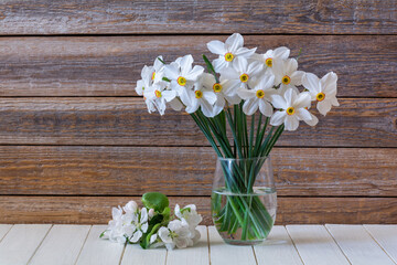 Bouquet of beautiful white flowers of daffodils in a glass vase on a wooden table