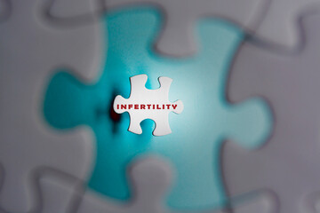 Infertility word on puzzle pieces isolated on blue background. IVF Treatment.