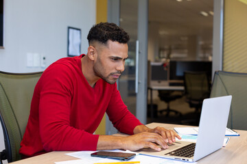 Fototapeta na wymiar Hispanic businessman using laptop while working in boardroom at modern workplace