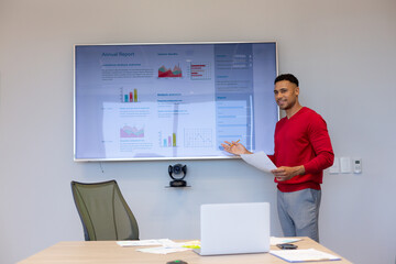Hispanic businessman giving presentation on television screen in boardroom during meeting at office