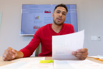 Portrait of confident male hispanic advisor with document explaining strategy in boardroom