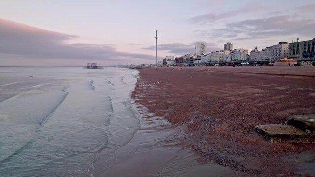 Drone slowly flies along empty beach towards Brighton i360 in the stunning morning, UK