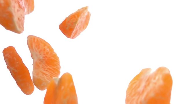 Close-up of the peeled tangerine pieces falling and rotating on white background