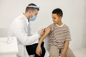 Male doctor doing a vaccination to a multiracional boy