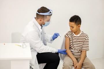 Obraz premium Male doctor stick a band-aid to a boy after a vaccination