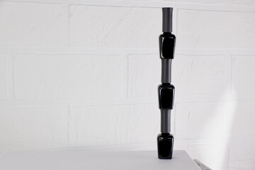 three black closed bottles of varnishes stand on top of each other on a light background. bottles of nail polish on a white background