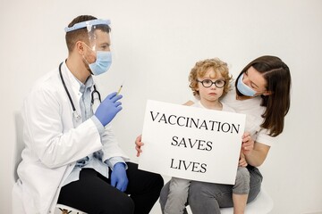 Little boy, mother and male doctor holding a poster about vaccination