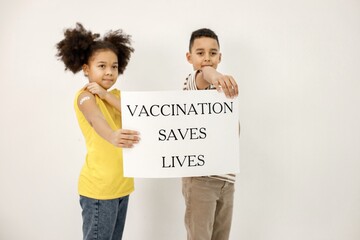 Two multiracial kids holding a poster that vaccination saved lives