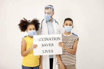 Two multiracial kids with doctor holding a poster that vaccination saved lives