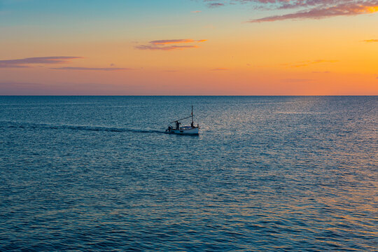 Llaut (t&iacute;pica barca de pesca de las Islas Baleares) llegando a puerto en Palma de Mallorca a la puesta de sol.