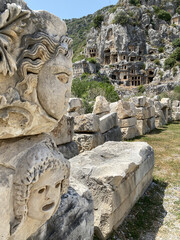 Historical Stone faces bas relief and ancient theater at Myra ancient city. Rock-cut tombs Ruins in Lycia region, Demre, Antalya, Turkey. Archeological remains of the Lycian rock cut tombs