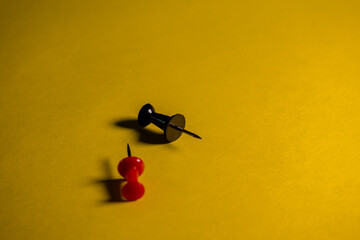 Black and red pushpins on a yellow background