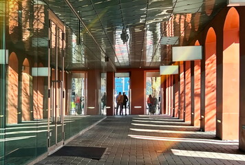  sun beam on shop vitrines  men and  women walk , orange modern buildings windows glass reflection...